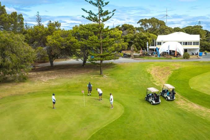 Golfers putting with the clubhouse behind